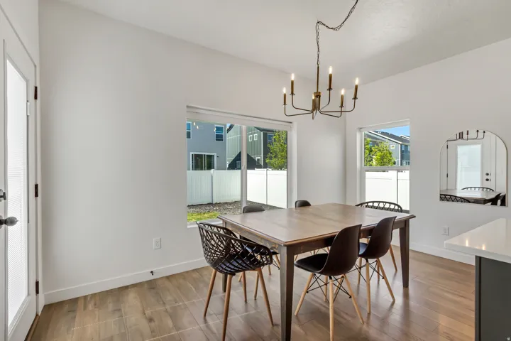 Spacious dining area featuring wood-finish flooring, multiple windows, and an overhead chandelier