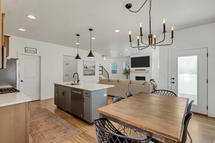 Open-concept living area featuring a kitchen island with sink and pendant lighting, wood-finish flooring, and a fireplace in the living space
