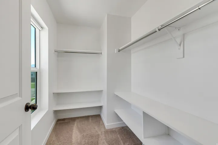 Spacious walk-in closet featuring built-in shelving, multiple hanging rods, and abundant storage capacity