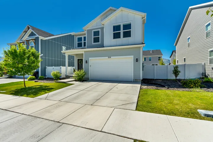 Contemporary exterior featuring light gray and white siding, an attached garage, a concrete driveway, and a welcoming front porch