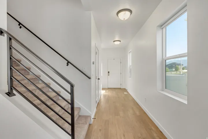 Light wood-finish flooring, white walls, and a modern black metal staircase railing