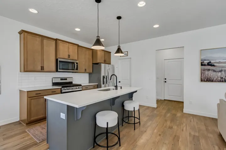 Kitchen featuring wood-finish cabinetry, stainless steel appliances, a center island with a light-colored countertop, and recessed lighting