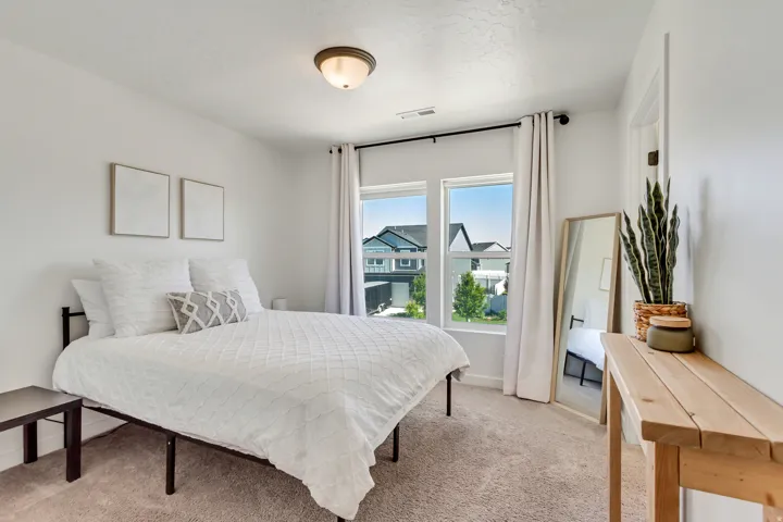 Recessed lighting, light-colored carpeting, two large windows with curtain rods, and a door frame