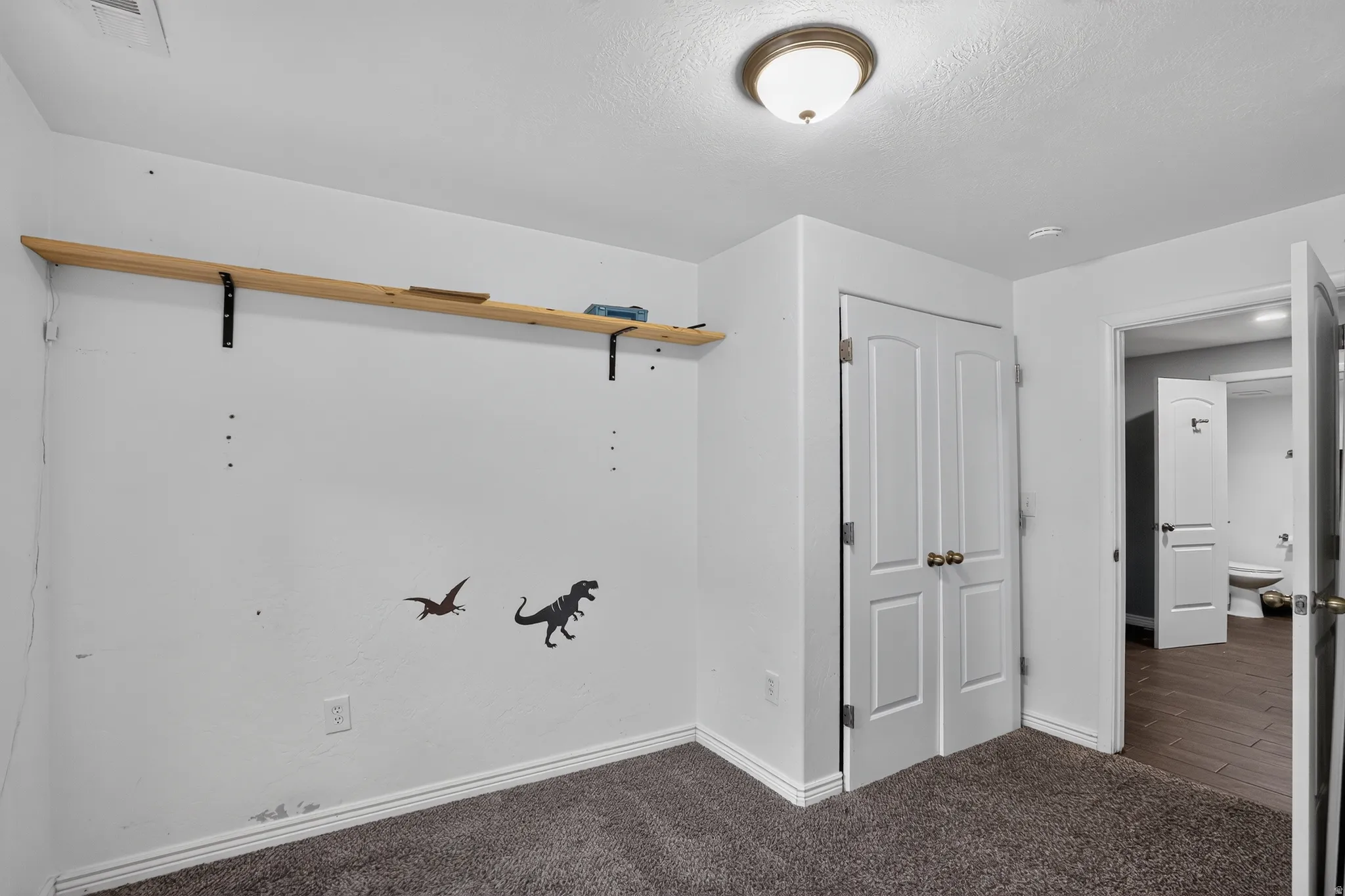 Carpeted room featuring a ceiling-mounted light fixture, white walls, and white baseboards