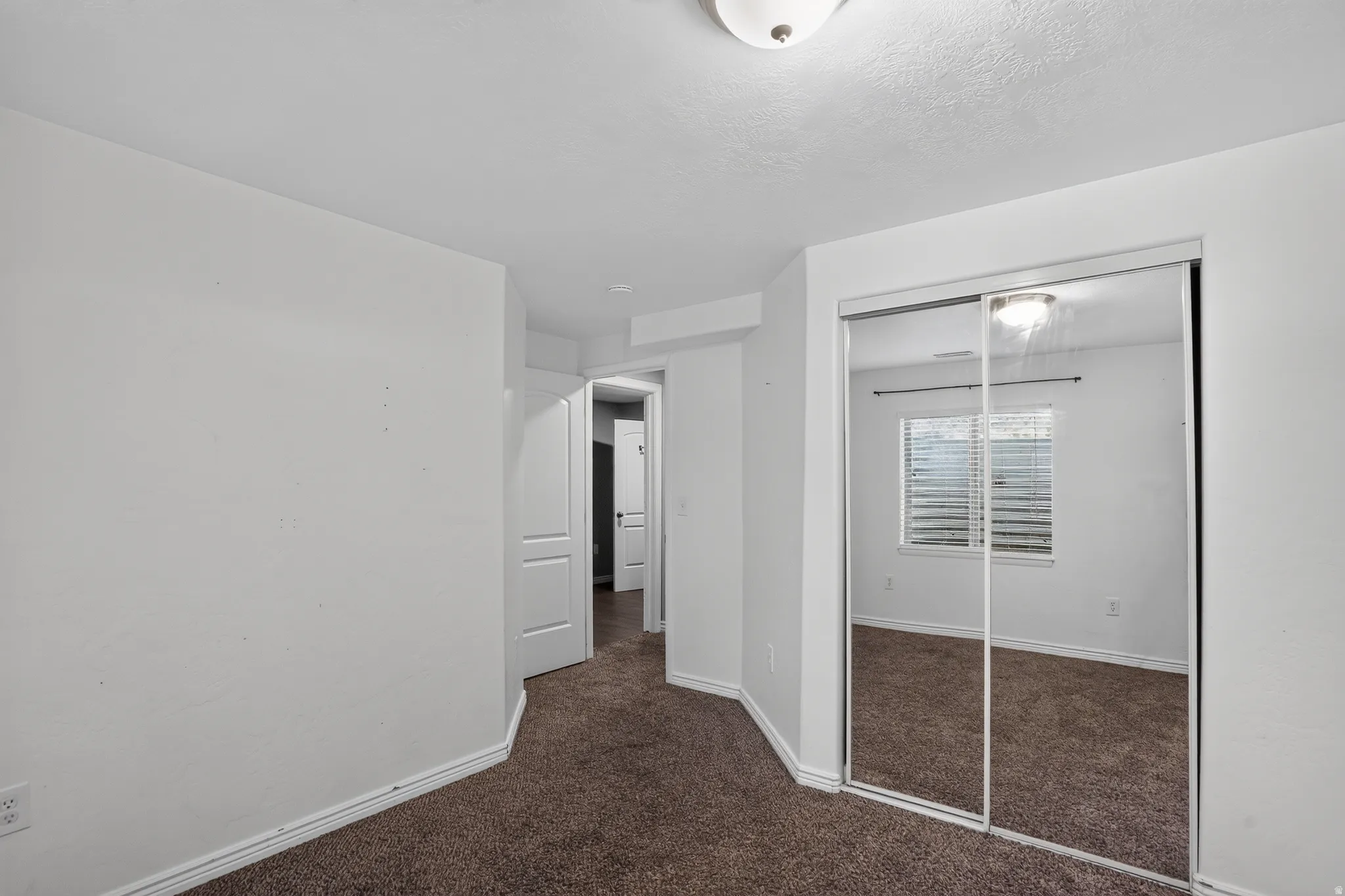 Mirrored sliding closet doors with white trim, brown carpet, white walls, and a recessed ceiling light fixture