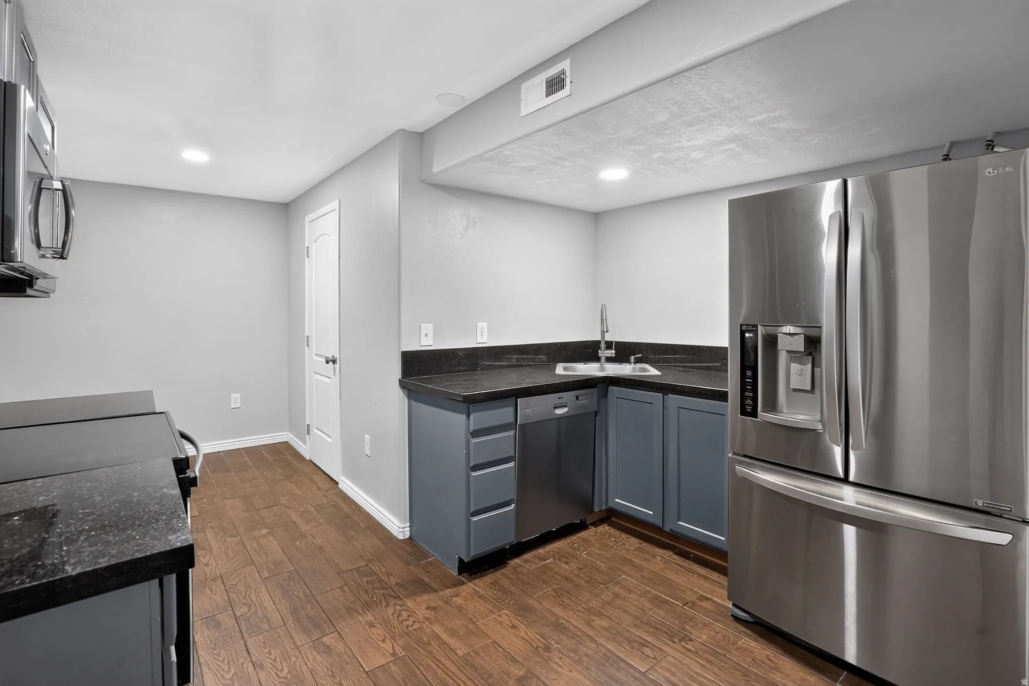Kitchen featuring wood-finish flooring, dark countertops, and stainless steel appliances