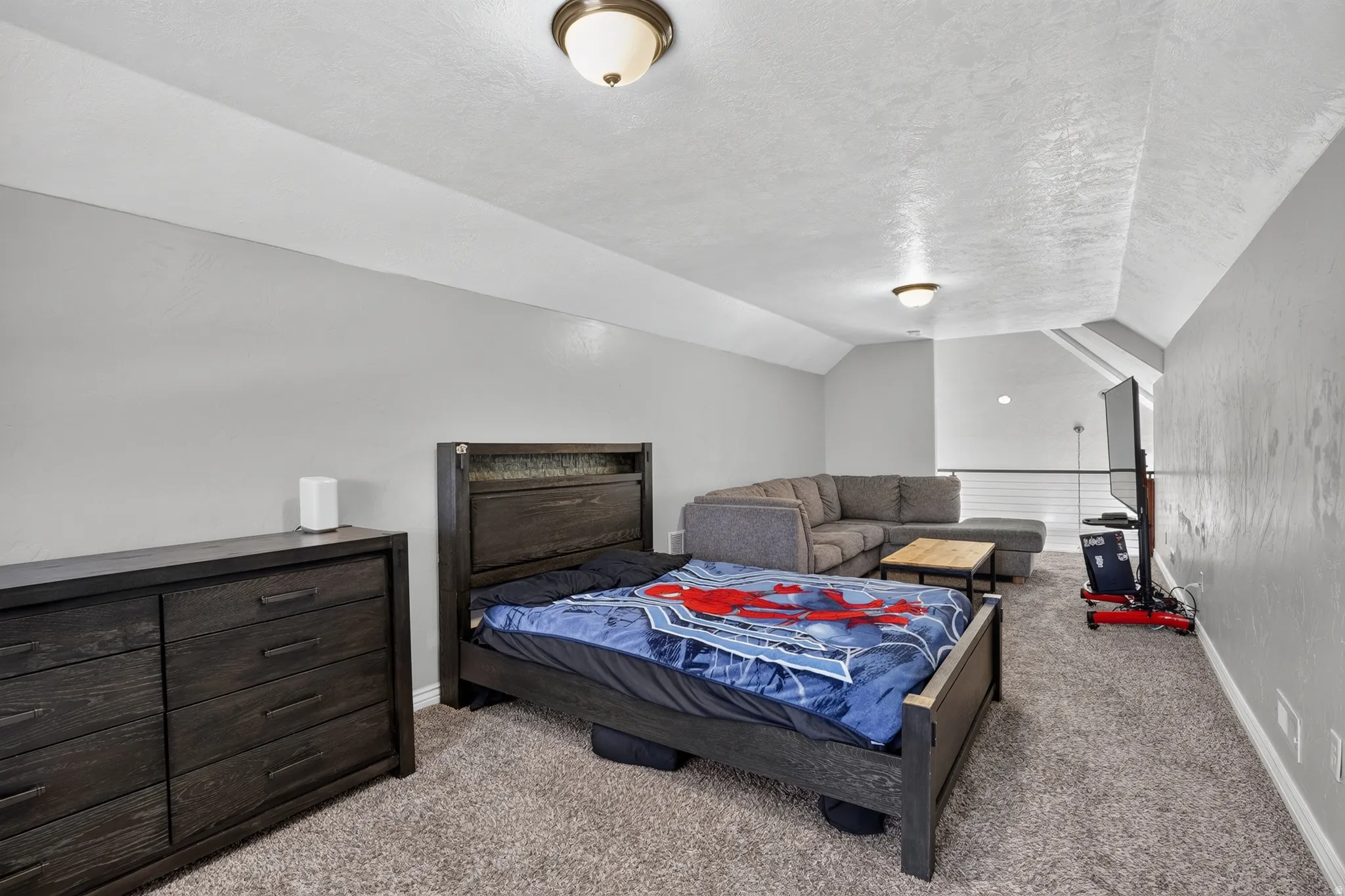 Versatile loft space featuring sloped ceilings, textured carpeting, and recessed lighting