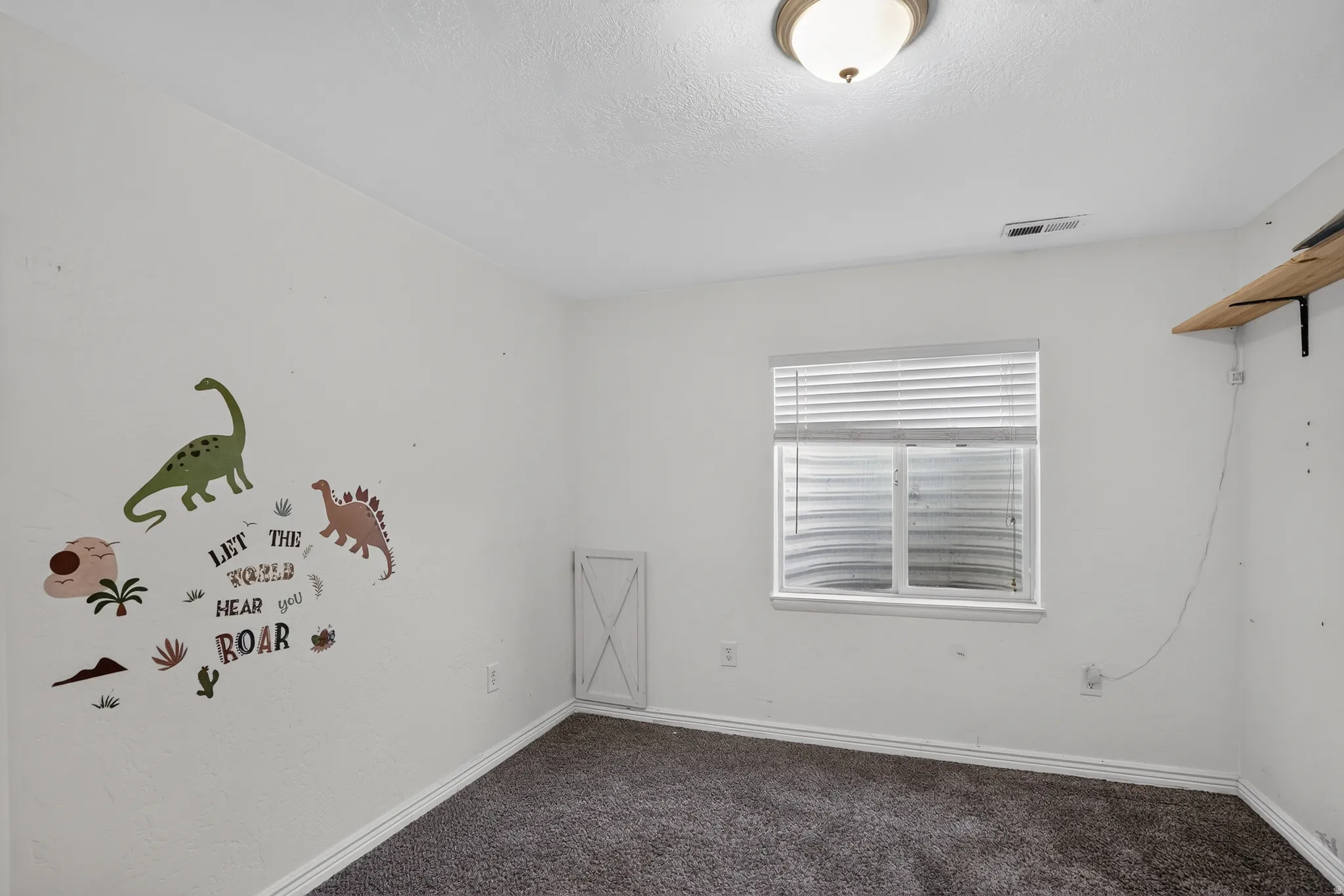 Carpeted room with a window featuring horizontal blinds