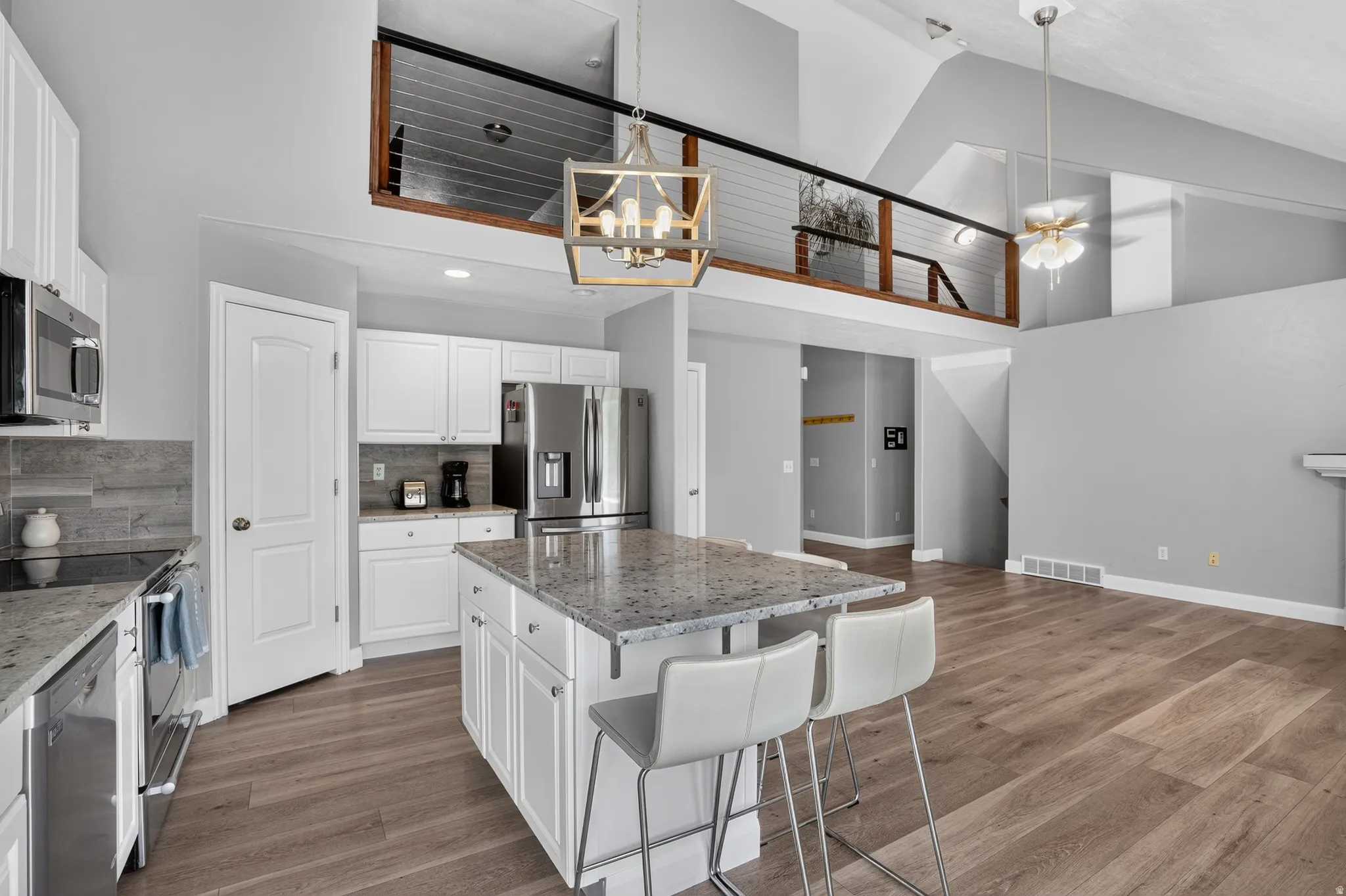 Open-concept kitchen with white cabinetry and stainless steel appliances