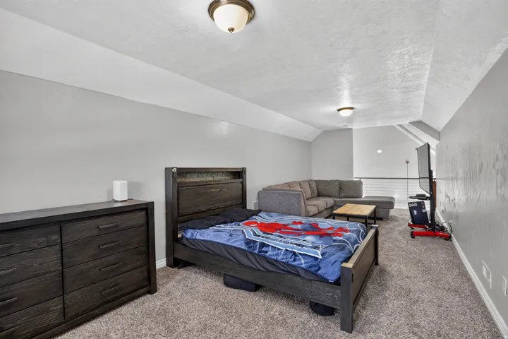 Versatile loft space featuring sloped ceilings, textured carpeting, and recessed lighting