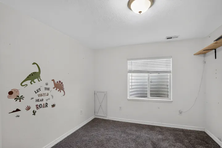 Carpeted room with a window featuring horizontal blinds