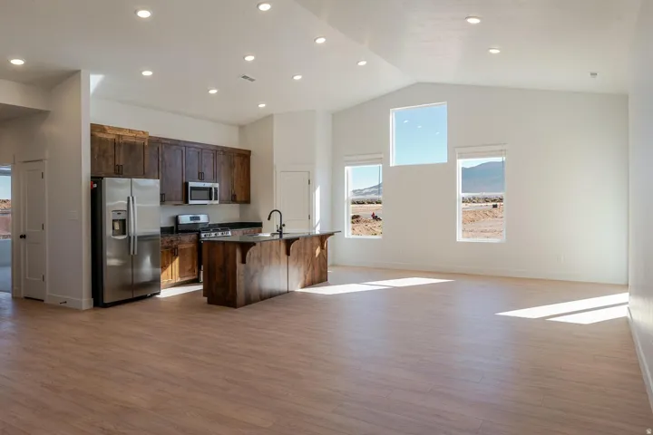Spacious open-concept living area featuring a vaulted ceiling and wood-finish flooring