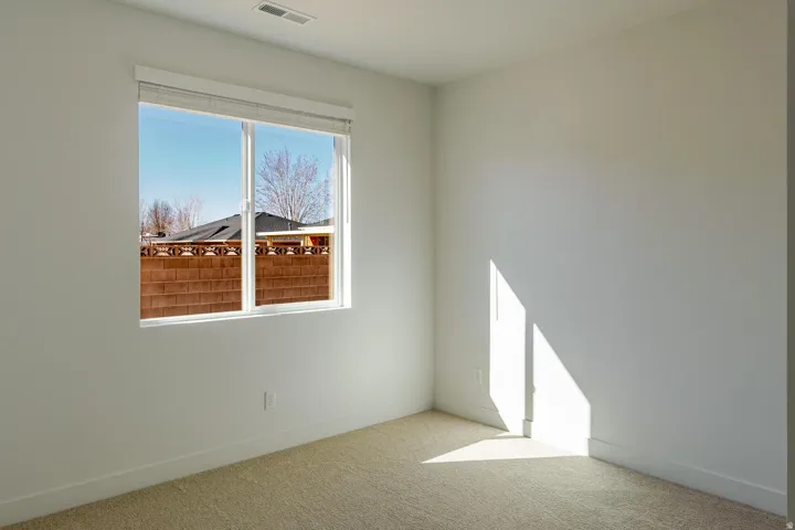 Neutral wall color, wall-to-wall carpeting, single window with roller shade, and white trim