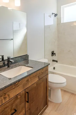 Wood-finish vanity with an undermount sink and dark countertop