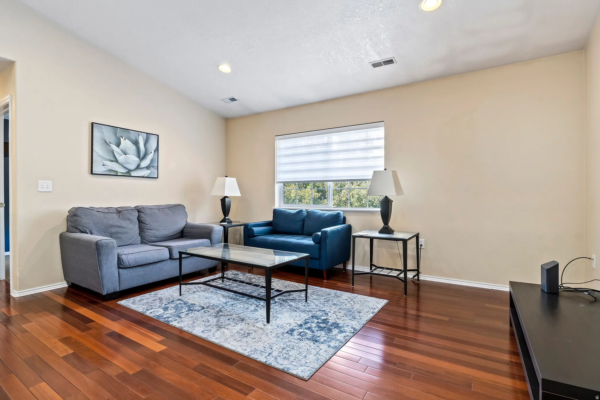 Vaulted ceiling, recessed lighting, wood-finish flooring, neutral wall paint, and a large window with blinds
