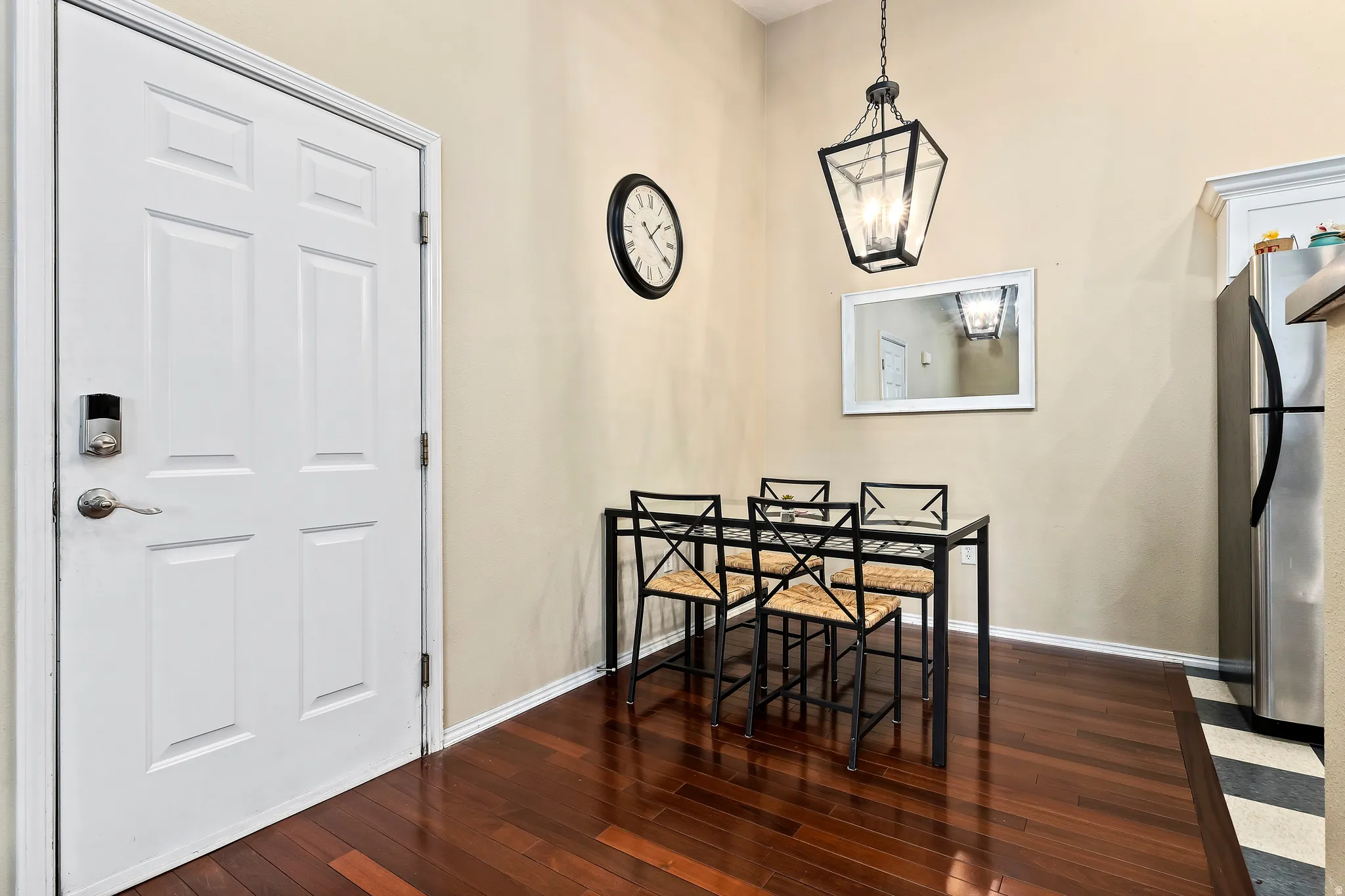 Hardwood-finish flooring, white paneled door, digital deadbolt, recessed lighting, and stainless steel refrigerator
