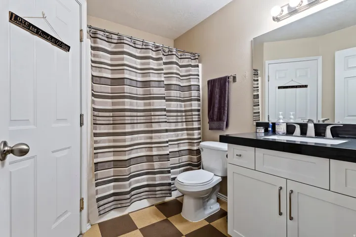 White vanity with dark countertop, undermount sink, and brushed nickel fixtures