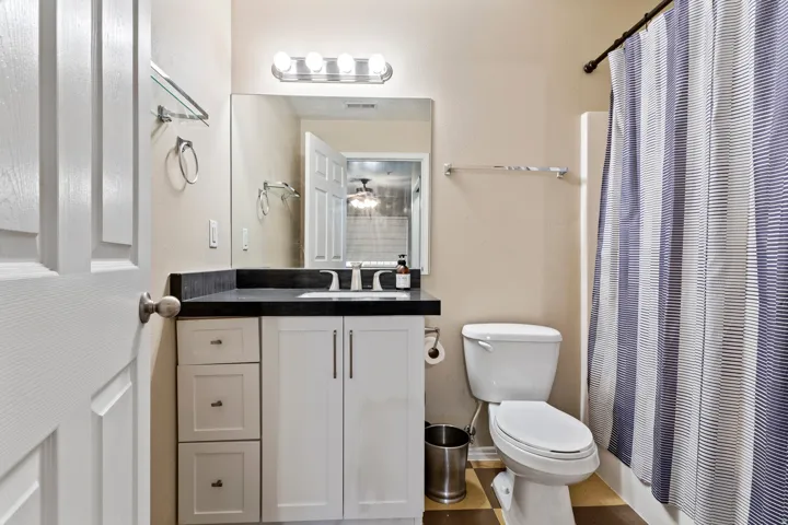 White vanity with black countertop, under-mount sink, and chrome faucet