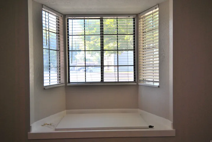 Bay window with white horizontal blinds and a built-in window seat