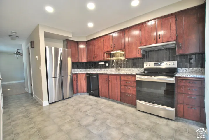 Kitchen featuring wood-finish cabinetry, stainless steel appliances, granite countertops, and a subway tile backsplash