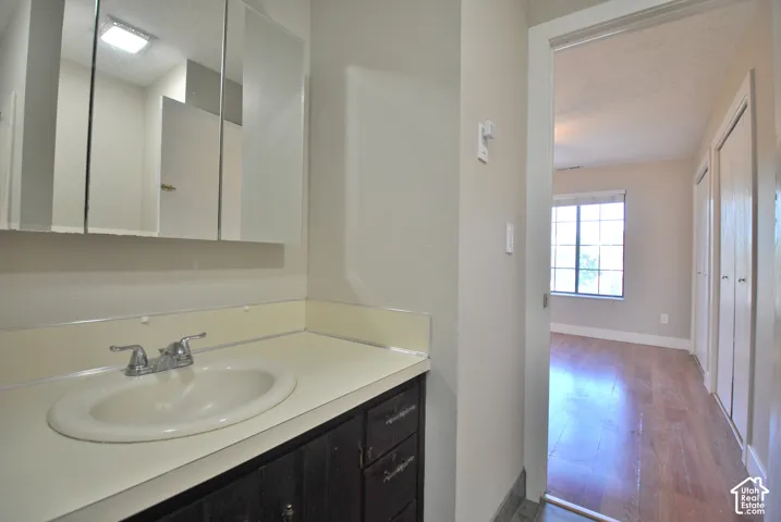 Bathroom connects to larger bedroom with vanity with an integrated sink and chrome faucet