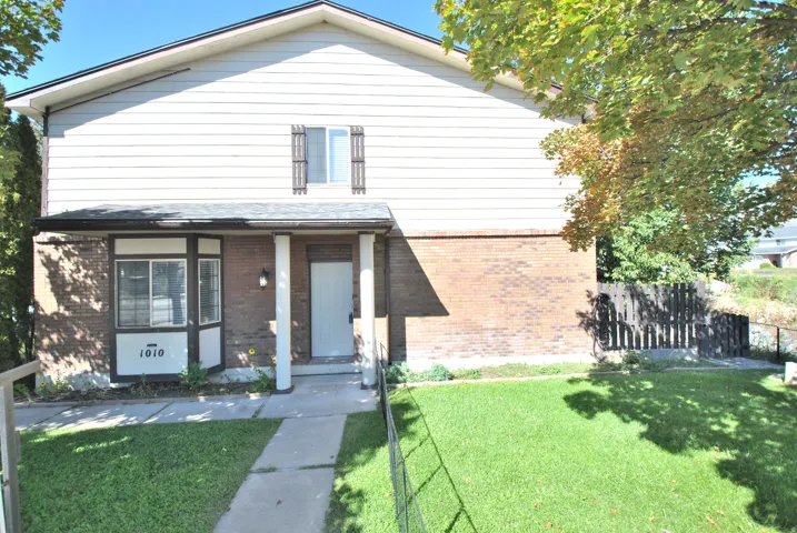 Two-story exterior with brick and siding facade, covered entry with columns, bay window, and front lawn