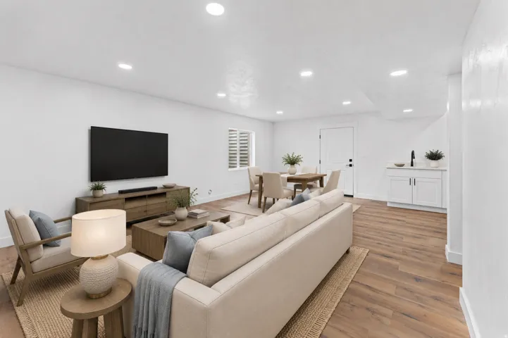 Open-concept living area featuring a neutral color palette, recessed ceiling lighting, and wood-finish flooring throughout