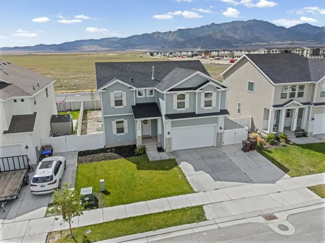 Two-story residence featuring a light blue and gray exterior with a two-car attached garage, concrete driveway, and manicured front lawn