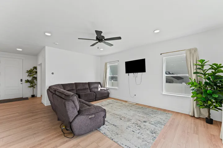 Recessed lighting, wood-finish flooring, white walls, ceiling fan, and white trim windows