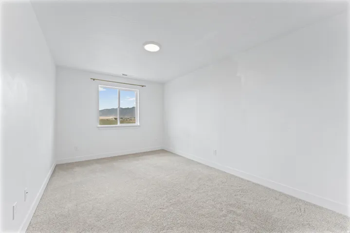 Recessed ceiling lighting, white walls, light-toned carpet, and a framed window