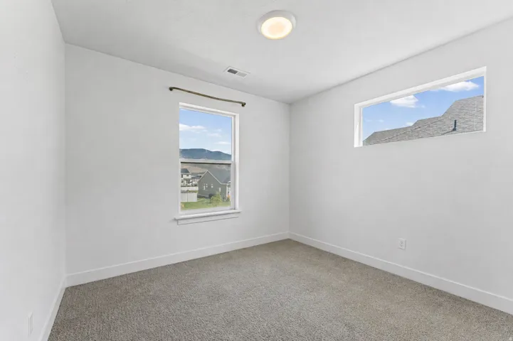 Neutral wall paint, carpet flooring, a window with a curtain rod, a transom window, and a flush mount ceiling light