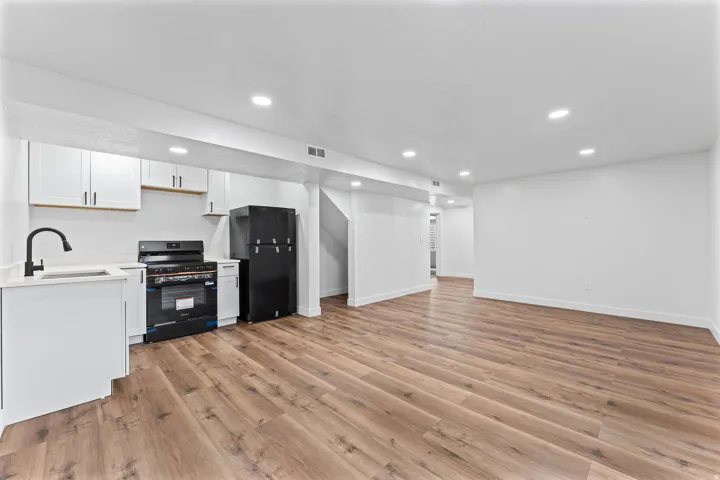 Contemporary kitchen features white cabinetry with matte black hardware, quartz countertops, and a black gooseneck faucet