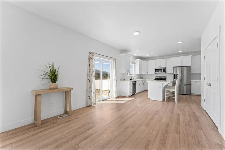 Spacious open-concept living area with wood-finish flooring, recessed lighting, and a sliding glass door