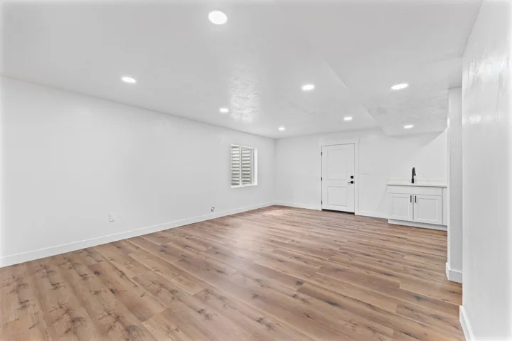 Recessed ceiling lighting, wood-finish flooring, built-in cabinetry with a countertop, and a window with plantation shutters