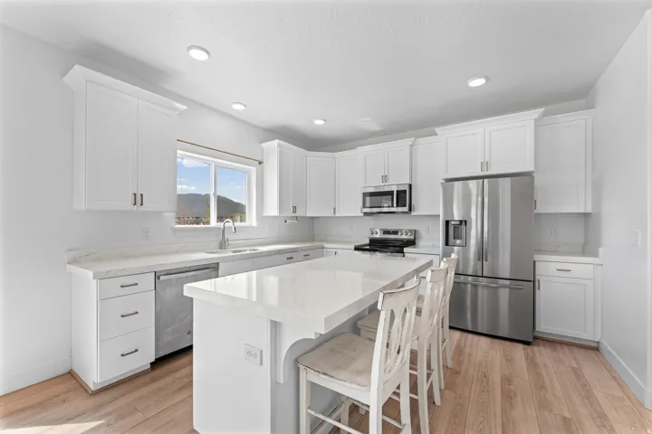 Full kitchen featuring white cabinetry, light-toned wood-finish flooring, recessed lighting, and stainless steel appliances