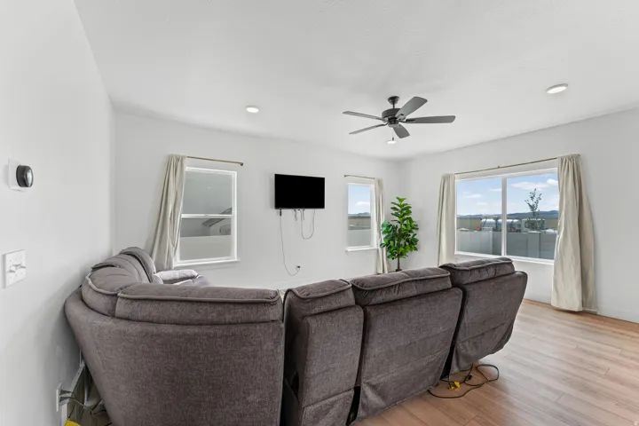 Open-concept living area with wood-finish flooring, recessed lighting, and a ceiling fan