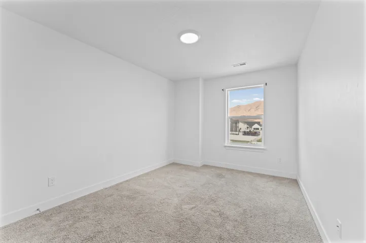 Neutral wall colors, recessed ceiling lighting, light-toned carpeting, and a window with mountain scenery