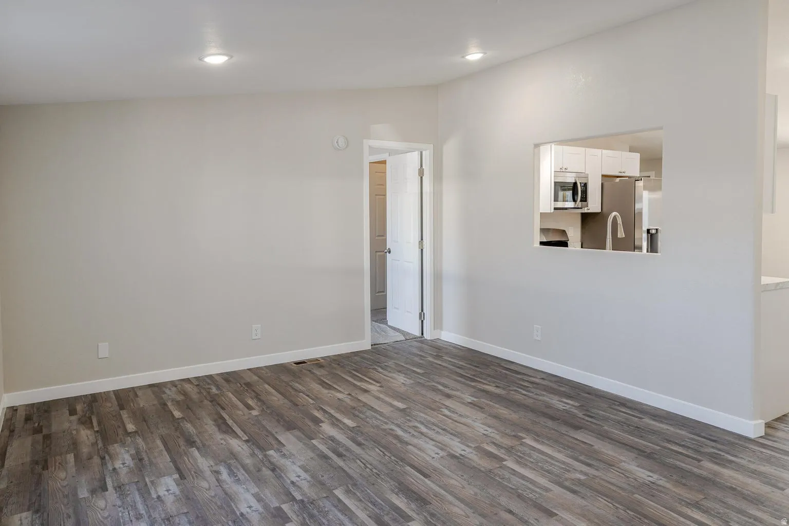 Wood-finish flooring, recessed lighting, and a pass-through window to the kitchen