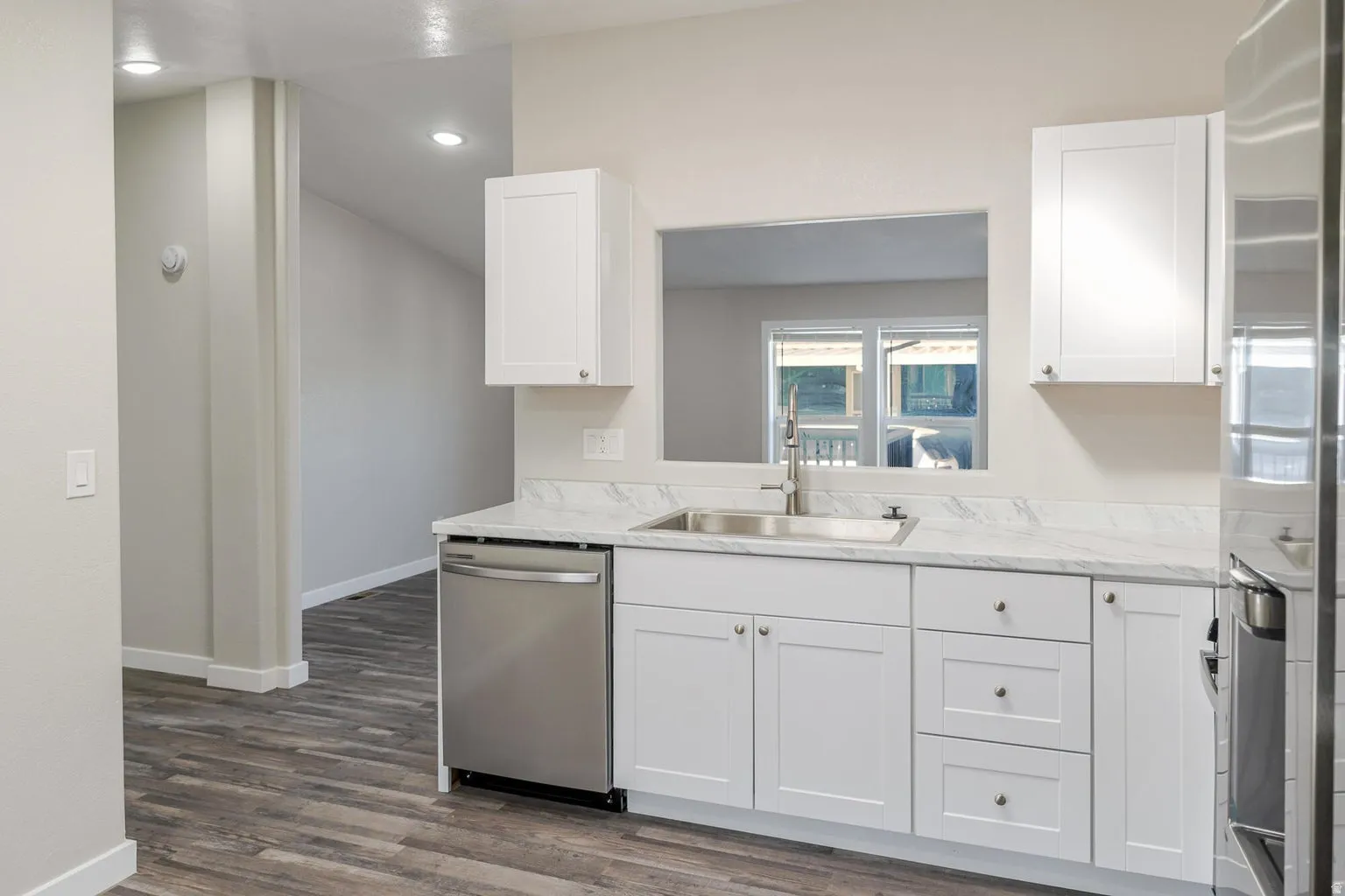 Kitchen featuring white shaker cabinetry, stainless steel appliances, a stainless steel sink, and light-toned countertops