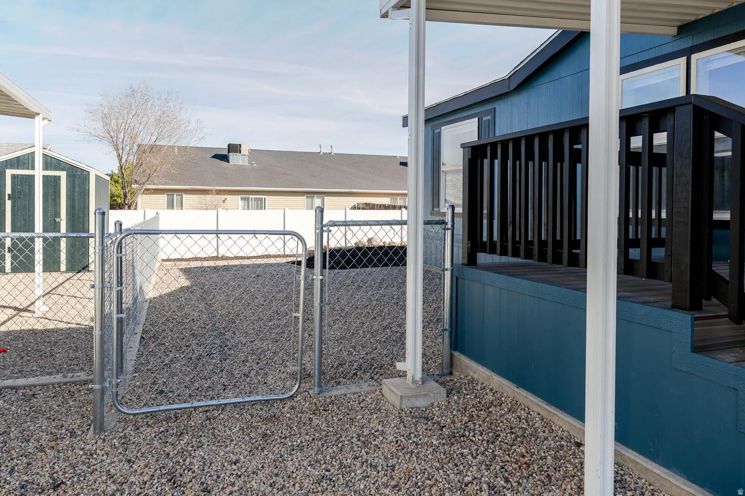 Gravel ground cover, chain link fencing, a storage shed, and a covered patio area