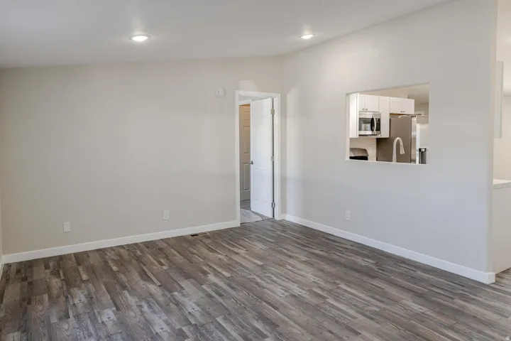 Wood-finish flooring, recessed lighting, and a pass-through window to the kitchen