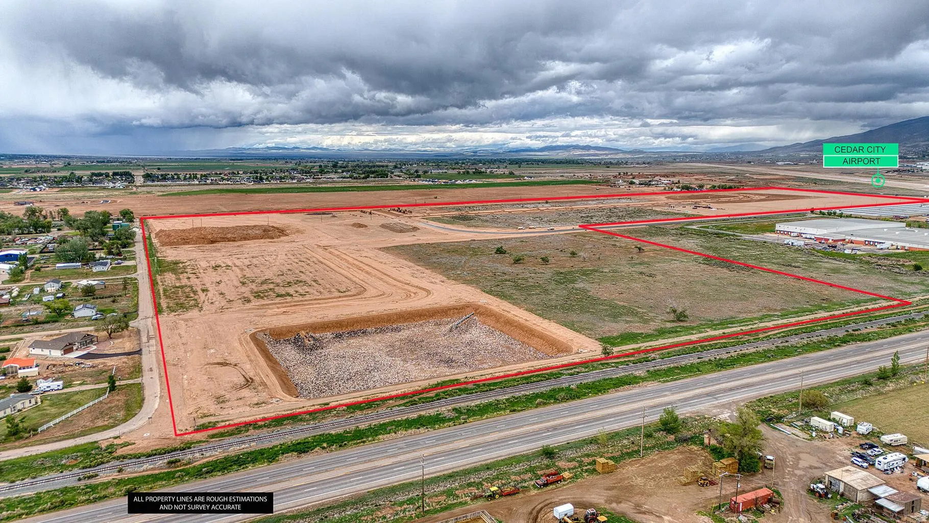 Expansive land parcel with visible property lines, a graded area, and a paved road frontage