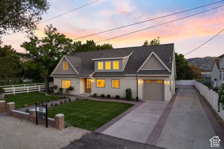 Contemporary home exterior with a light-colored brick facade, dark shingled roof, and an attached single-car garage