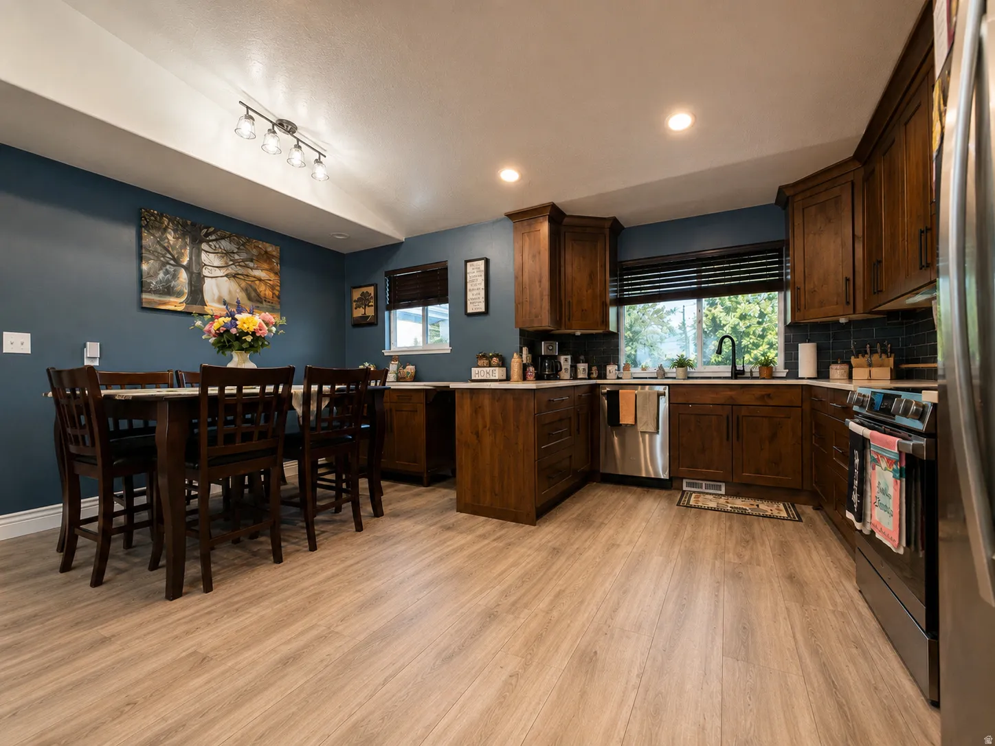 Spacious kitchen and dining area featuring dark wood cabinetry, stainless steel appliances, and a black subway tile backsplash