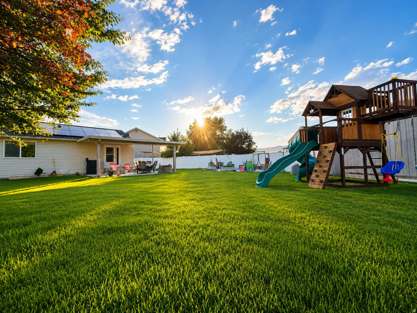 Expansive green lawn with a white privacy fence