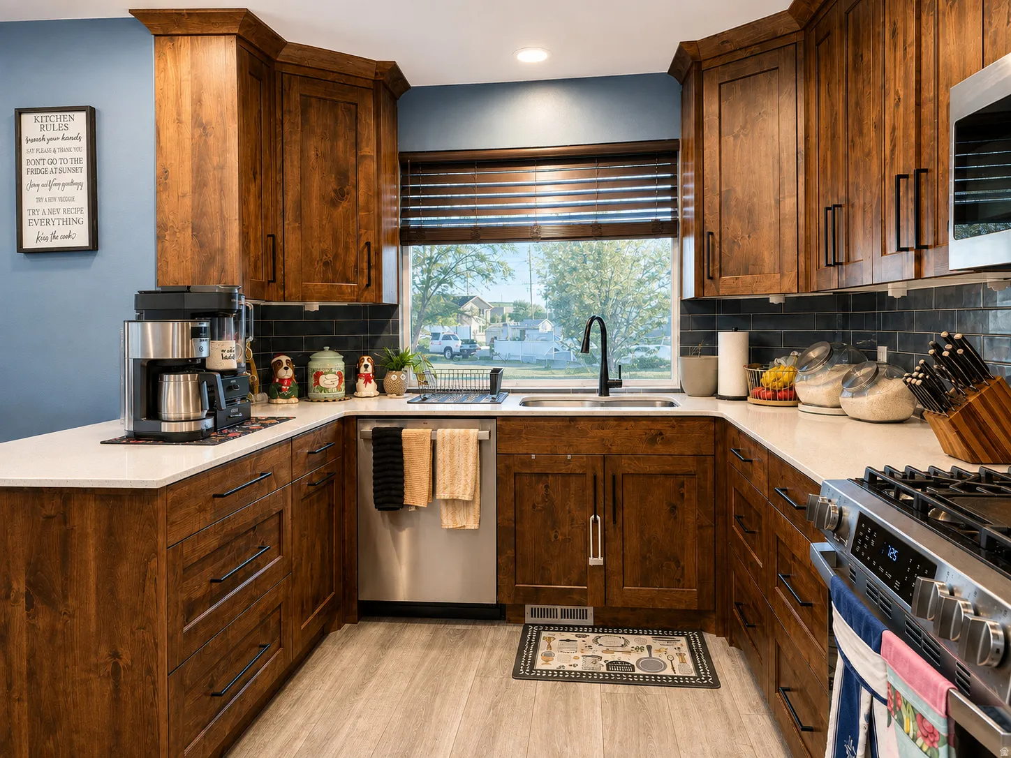 U-shaped kitchen featuring wood cabinetry, light countertops, subway tile backsplash, and stainless steel appliances