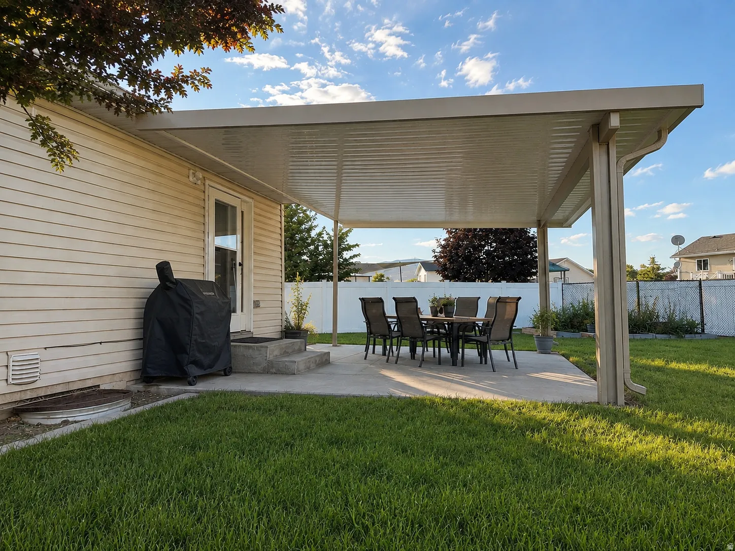Expansive concrete patio with a full-coverage awning structure, offering an exterior living space