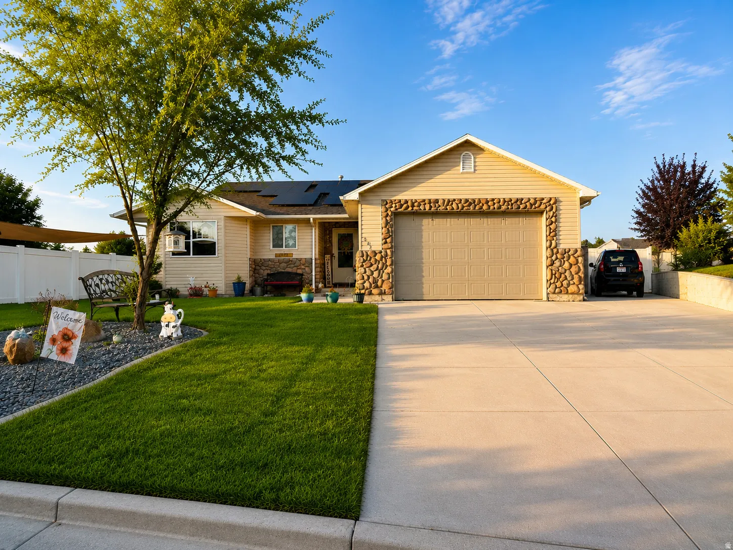 Exterior featuring tan siding, stone accents, and an attached two-car garage