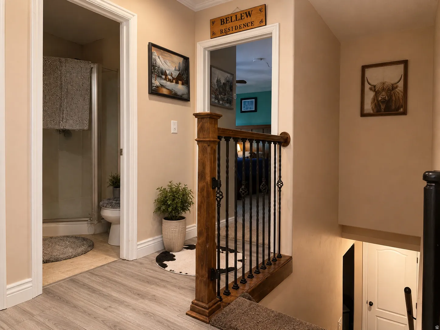 Wood-finish flooring, staircase with wood newel posts, wrought iron balusters, and a glass-enclosed shower