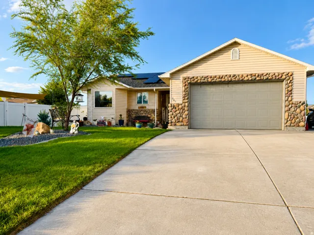 Exterior featuring stone accents, horizontal siding, a two-car garage, and a concrete driveway